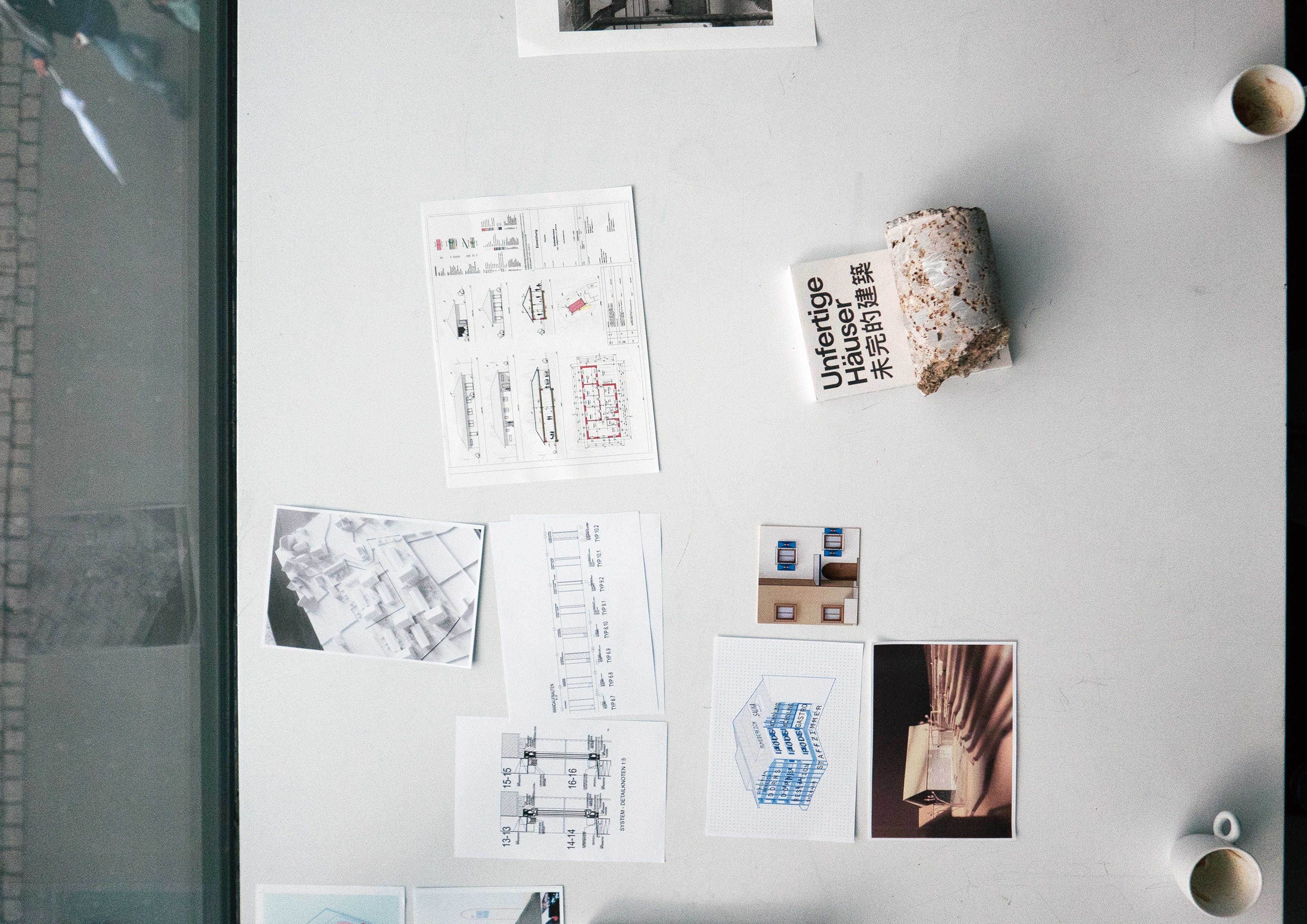 Top view of a table with drawings, photos, a material sample and the book 