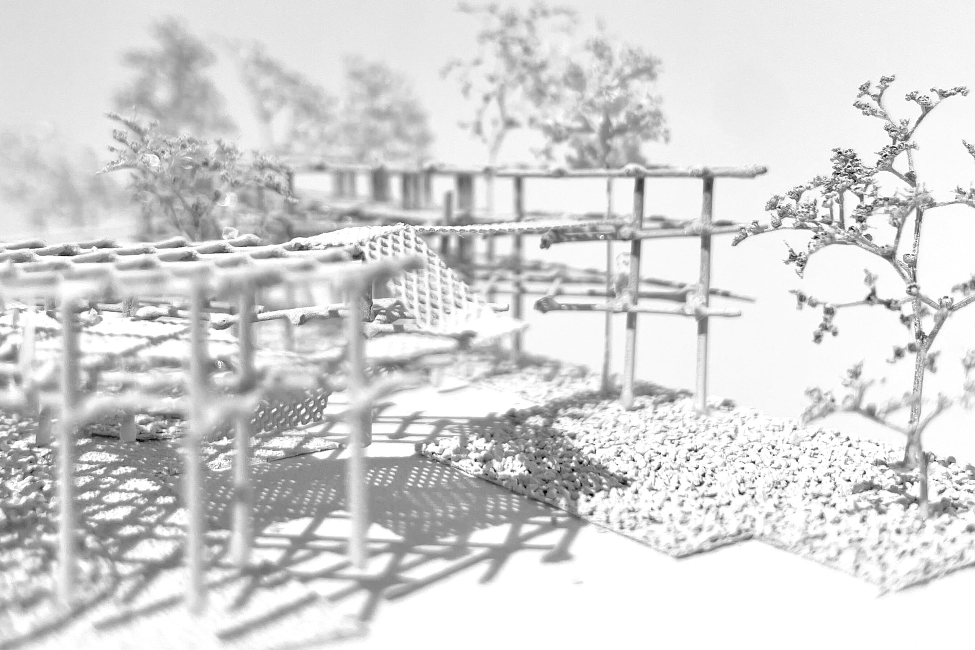 Model close-up: frames with mesh platforms and a model tree casting shadows on gravel ground asphalt kollektiv