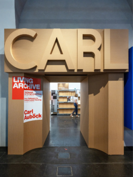 Eingangsportal der Carl-Auböck-Ausstellung: Kartonbuchstaben „CARL“, Plakat „Living Archive“, dahinter Archivregale asphalt kollektiv