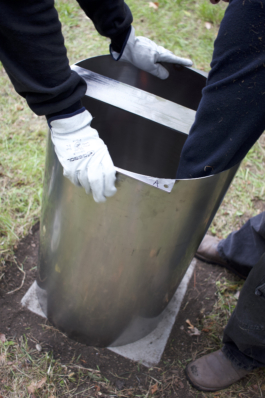 Gloved hands fitting a stainless steel cylinder leg onto its base in the lawn asphalt kollektiv