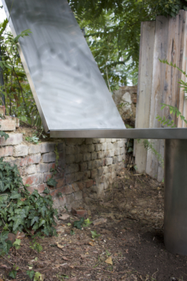 Folded-up half above the brick wall, the fixed tabletop continuing on its steel leg asphalt kollektiv